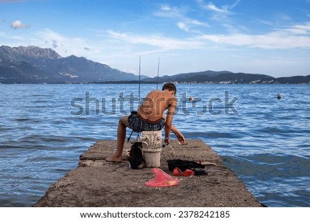 Boy and cat fishing at sea dock.