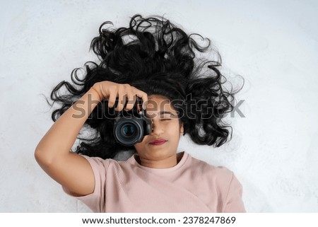 A girl lying on a white background and taking a picture with a professional camera