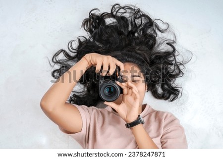 A girl lying on a white background and taking a picture with a professional camera