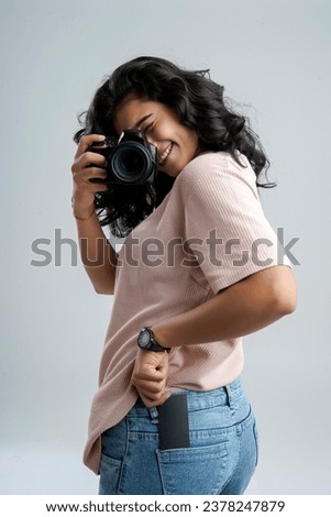 A girl with a camera and a card in her back pocket, embodying a blend of modernity and anticipation.