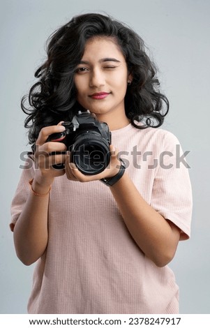 Young woman with professional camera isolated on background Royalty-Free Stock Photo #2378247917