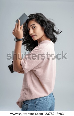 A young girl, holding a camera and a credit or empty card, ready to embark on an online shopping photography adventure.