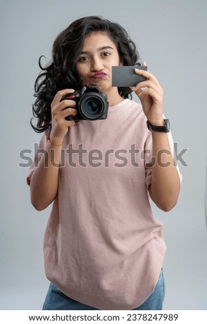 A young girl, holding a camera and a credit or empty card, ready to embark on an online shopping photography adventure.
