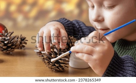 A child makes decorations for Christmas. Christmas decor made from natural materials. Christmas decorations made from pine cones. Children's creativity