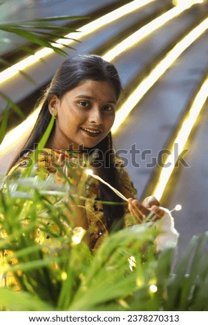 Indian girl smiling on the decorated stairs with fancy lights on the plant decorated for diwali Indian festival