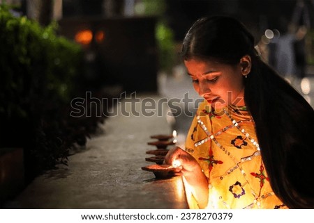 Indian girl lighting the diya for diwali