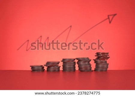 Financial concept on investment, rate, banking, etc. Stacked coins on red background with a blurry arrow pointing up at the back. Copy space for text, advertisement, etc. 