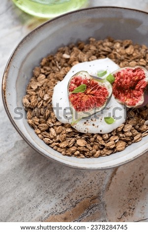 Granola served with torn figs and greek yogurt in a grey bowl, vertical shot, selective focus, middle close-up