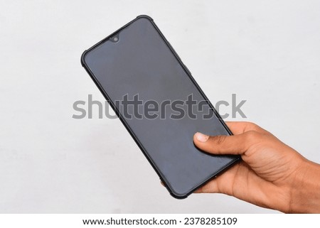 Child hand holding black cellphone with black screen.