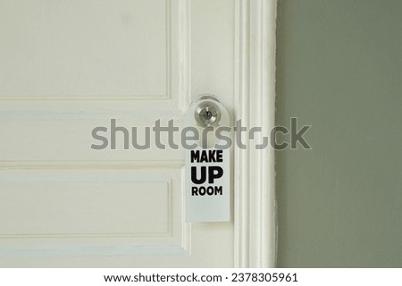white door hanger the message says Make Up Room that hotel guests hang on the doorknob outside the room. to allow housekeepers to come and clean the room.                                