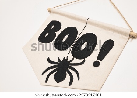 A banner with 'Boo!' and cut spider hanging on the wall, setting a Halloween mood - a perfect addition to your spooky decor. 