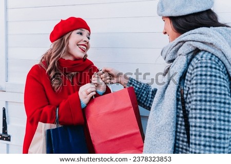Portrait of a cute woman in beret giving a gift to a friend in the street