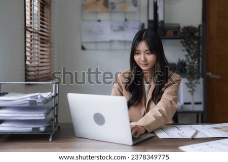 Female architect work to inspection construction plan on laptop and blueprint of building project.