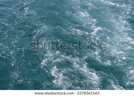 Blue sea with small white waves behind a boat, fill the frame photo
