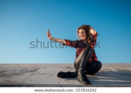 Young woman in hipster outfit sitting and taking selfie  