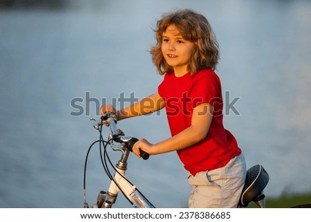 Kid riding bike. Happy kid boy riding bike in summer park.