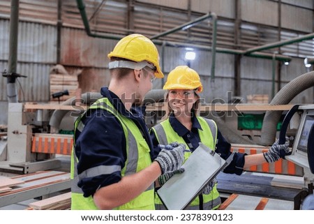 Two Caucasian dedicated timber professionals collaborate in a busy workshop, discussing plans and ensuring every detail is perfected for their project Royalty-Free Stock Photo #2378390123