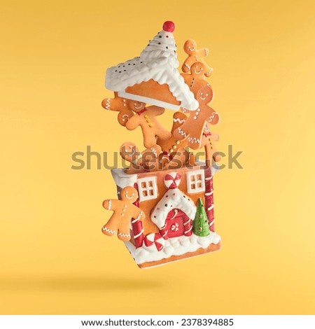 Christmas card. Falling in the air Christmas gingerbread cookies isolated on yellow background. Gingebread house and man cookies. Christmas levitation or zero gravity conception. 
