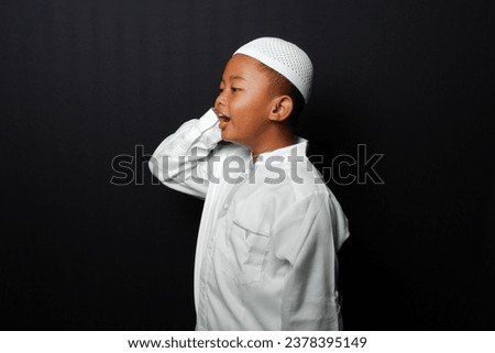 Asian Muslim kid wearing moslem clothes (Koko) . He is on the call to prayer or adzan