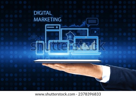 Close up of man hand holding smartphone with creative blue gadgets and business chart hologram on blurry pixel background. Digital marketing, finance, social network and online service concept