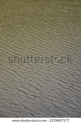 The texture of dark river water under the influence of wind, imprinted in perspective. Vertical image