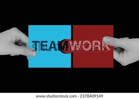 Teamwork letters jigsaw being connected by two business man’s hands to make the word completed on black background.