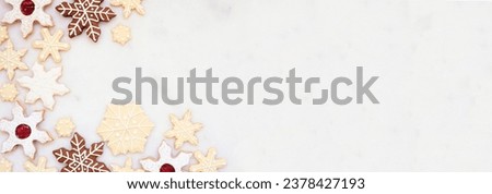 Christmas baking corner border with a variety of snowflake cookies. Top view on a white marble banner background with copy space. Holiday baking concept.