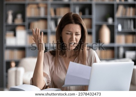 Indignant woman reading letter sit at table at home, housewife received bad news resented by utilities price go up, lessor raised cost of rented housing, debt notice from bank, money problems concept Royalty-Free Stock Photo #2378432473