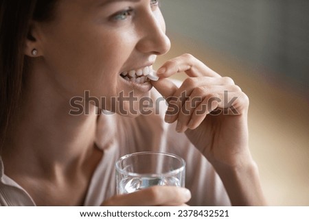 Close up face smiling young 35s woman holding glass taking of daily dose water-soluble vitamins pill, millennial female drinking prescribed medication, get nutrition supplements, health care concept Royalty-Free Stock Photo #2378432521
