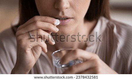 Close up sick woman holds glass of water takes pill drug or medicine for reduce pain, depressed female use sedative antidepressant for improve mood state, contraceptives, pharmacy, healthcare concept Royalty-Free Stock Photo #2378432581