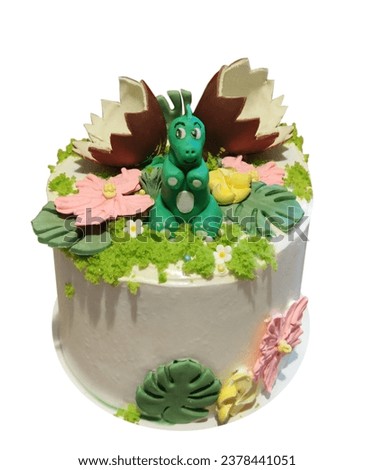 Cream cake decorated with a dragon figurine and chocolate eggs, isolated on a white background