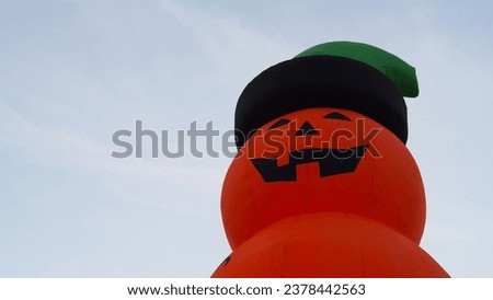 isolate Picture of an orange wind-up pumpkin doll on clear sky at the Halloween festival.