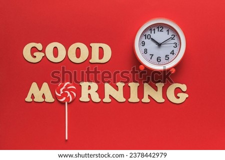 The inscription good morning, clock and lollipop on a red background. Good morning. A good day.