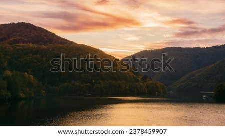 mountainous autumn landscape with lake at dusk. scenery in fall colors reflecting in the calm water. local tourism and relaxation concept. cluj county, romania
