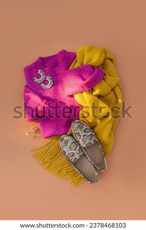 Pink sweater with scarf and loafers on orange background. Women's jumper stylish autumn or winter clothes. Fashion outfit. Cozy bright winter, fall look. Trendy  clothes collage. Flat lay, top view.