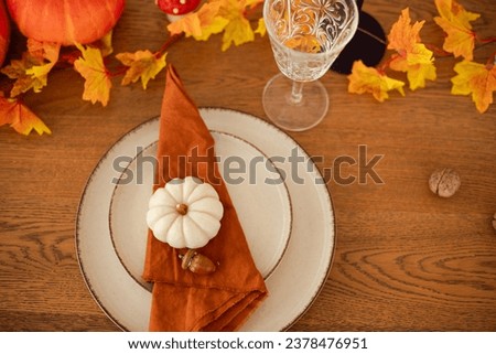 Autumn setting of the dinner table. Red and yellow leaves and pumpkins. Cute table decoration