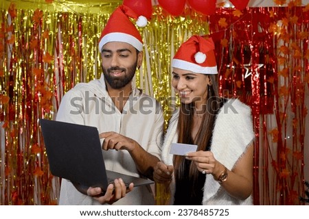 Happy couple celebrating Christmas with gifts and online shopping at home.
