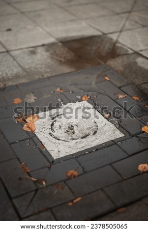A fountain of water from a hole in the paving stones in the square