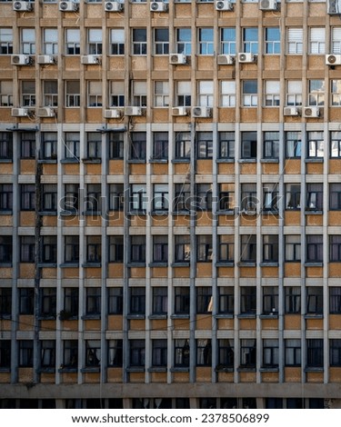Close-up of a building facade in Tel-Aviv, Israel, highlighting uniform windows, air conditioning units, and urban living, perfect for architectural and urban design themes
