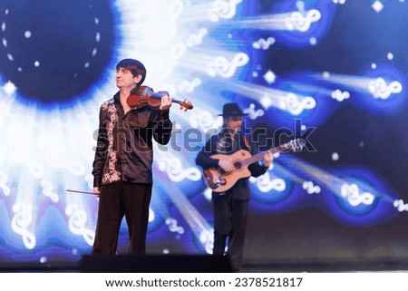 Smoke and light on the stage. Male musicians violinist and guitarist player perform a concert on stage