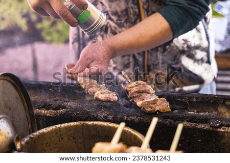 picture of a cook from a street kitchen seasoning skewers of meat, in Tokyo, Japan