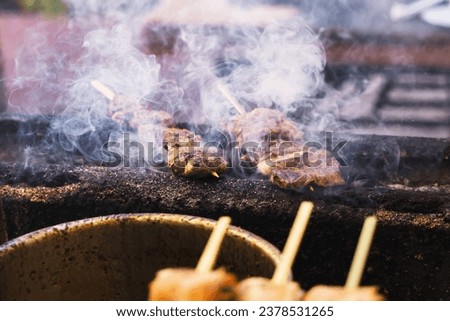 picture of smoking skewers of meat on a grill of a street kitchen