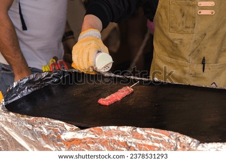 picture of a chef at a street kitchen seasoning a wagyu skewer at Tsujiki-market in Tokyo, Japan