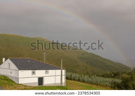 a rainbow in the mountains and a white house