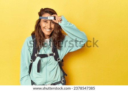 Middle aged hiker woman with backpack and frontal light on yellow Royalty-Free Stock Photo #2378547385