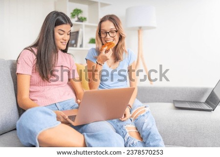 Friends eating pizza while studying using laptop together at home
