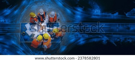 Top view of Architectural engineers putting their hands together on solar panel and his blueprints with Solar photovoltaic equipment and wind turbine on construction site. Royalty-Free Stock Photo #2378582801