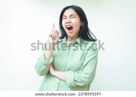 tired yawning asian woman pointing finger up to empty space and folding arms with eyes closed and mouth wide open just wakeup gesture wearing green oversiszed pajamas isolated on white Royalty-Free Stock Photo #2378595597
