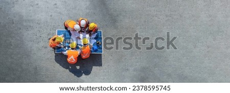 Top view of architect engineer working on solar panel and his blueprints with solar photovoltaic equipment and wind turbine on construction site. clean energy concept. copy space for text and design. Royalty-Free Stock Photo #2378595745