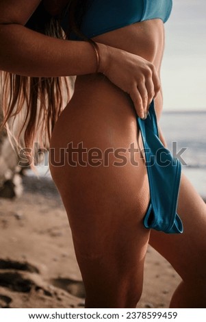 Woman summer travel sea. Happy tourist enjoy taking picture outdoors for memories. Woman traveler posing on the beach at sea, holding a bikini bottom in her hand, sharing travel adventure journey